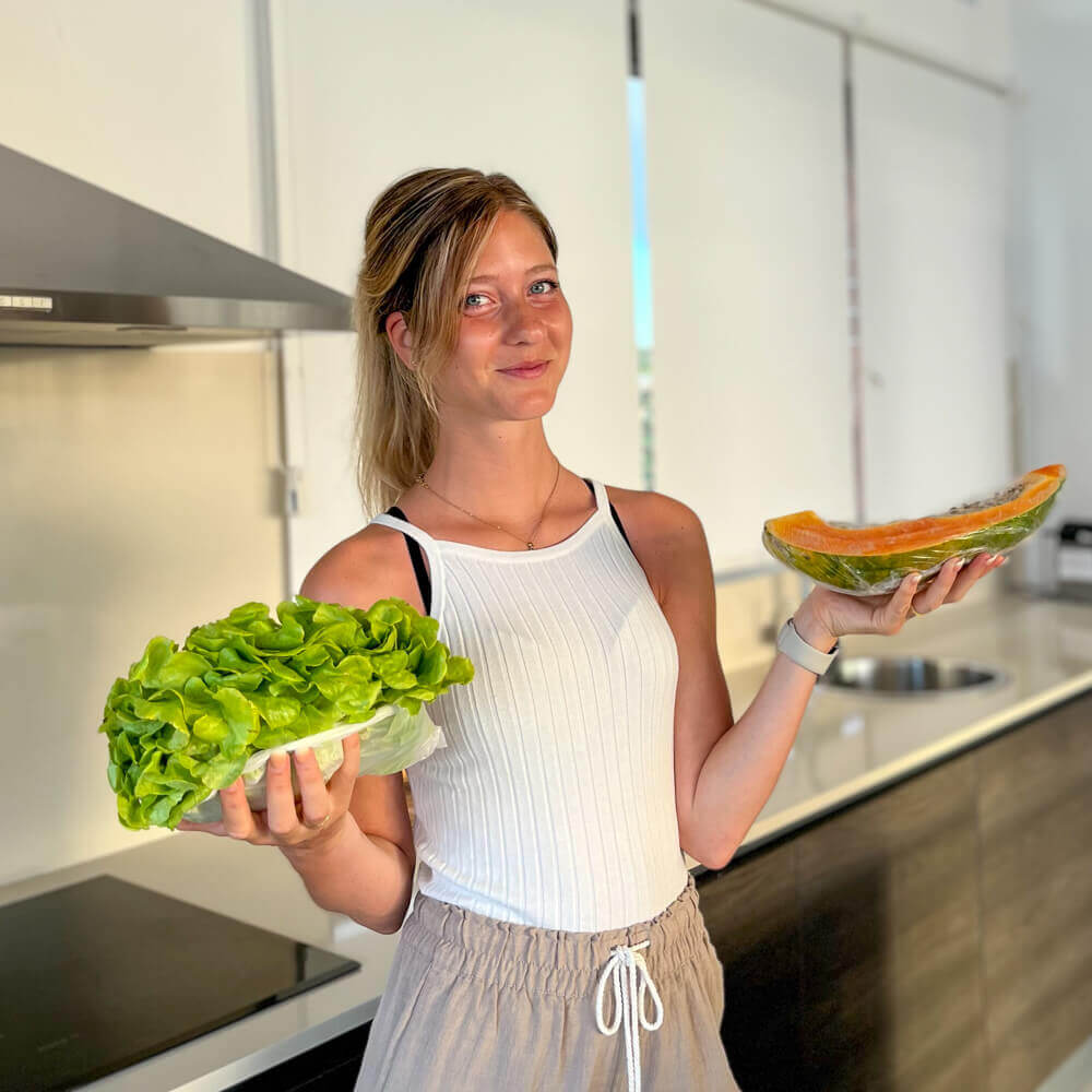 Voedingsdeskundige Lotte in de keuken met een krop sla en een papaya in haar handen.