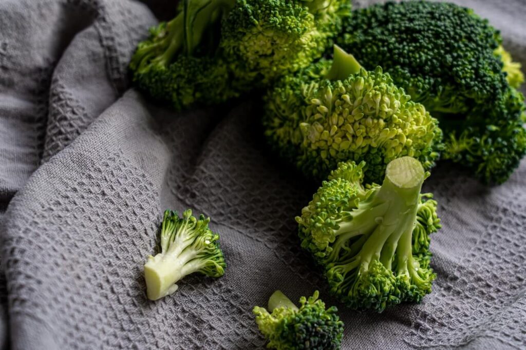 Groene broccoli in stukjes op een grijze theedoek.