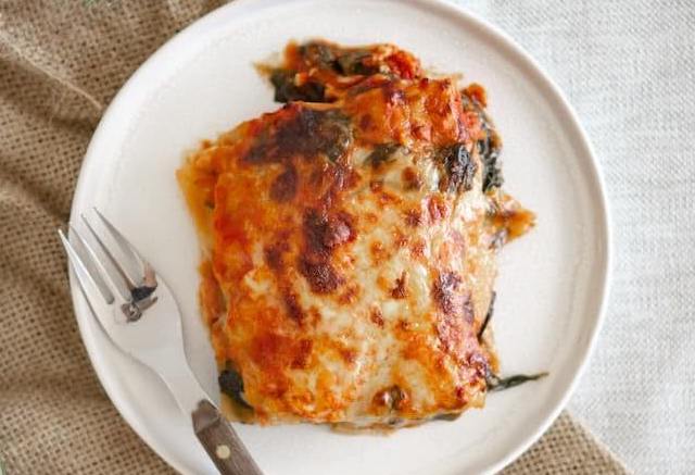 Een stuk courgette lasagne ovenschotel op een wit bord met een vork.