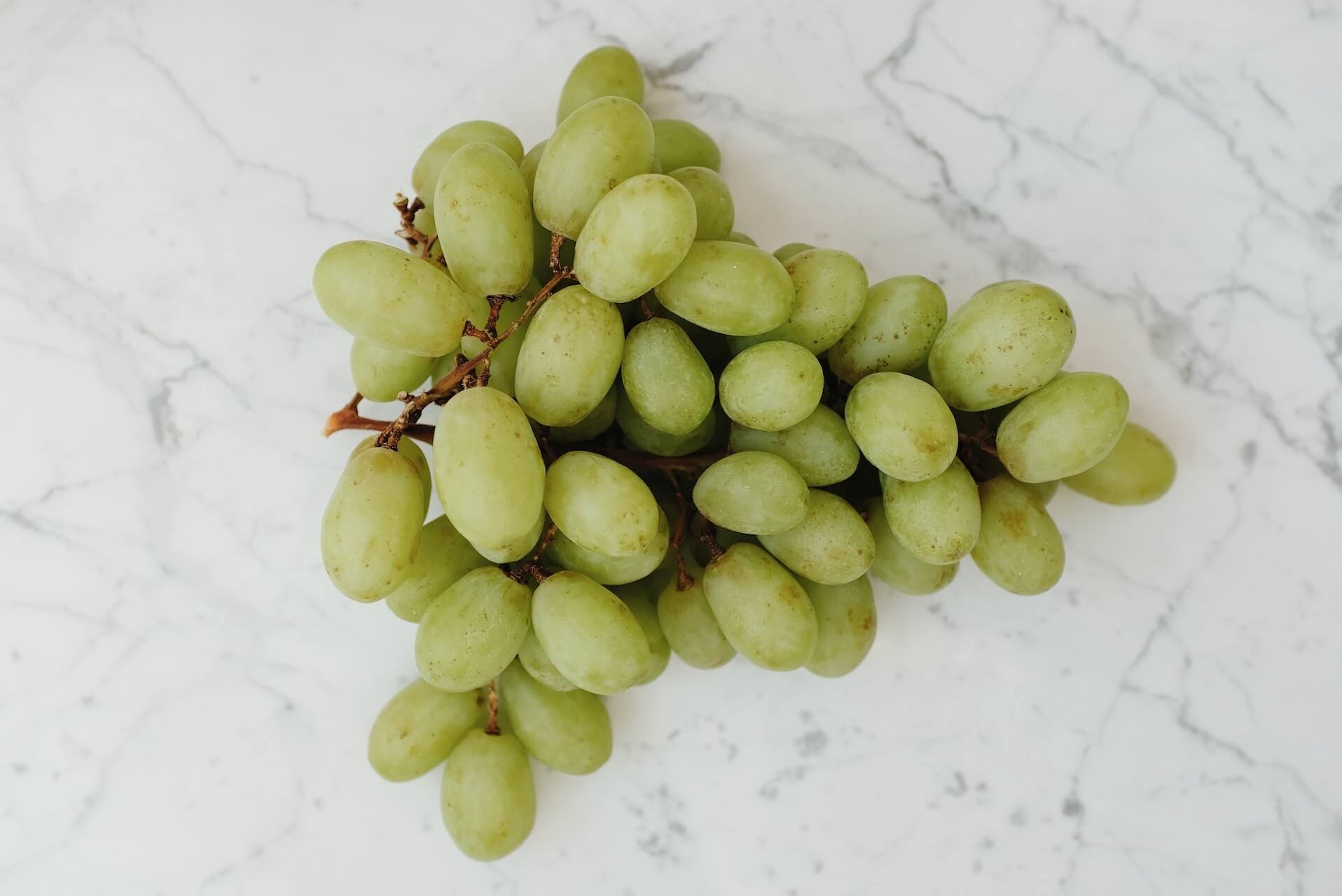 Een groene druiventros op een marmeren eettafel.